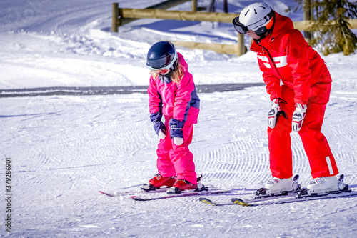 L'Alpe D'Huez, France 02.01.2019 Professional ski instructor is teaching a child to ski on a sunny day on a mountain slope resort. Family and children active vacation.