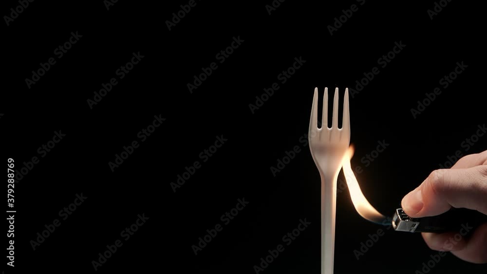 Hot flame gas lighter burns white disposable plastic fork. Say no to plastic concept.