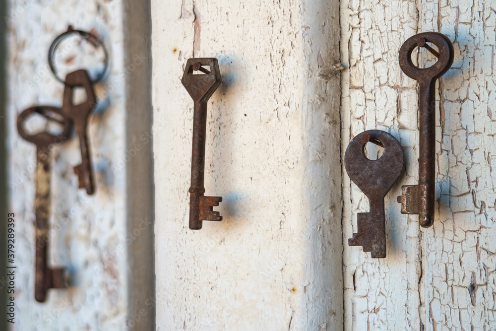 Old rusty keys on the shabby wooden door frame with broken white paint Old rusty keys on the shabby wooden door frame with broken white paint