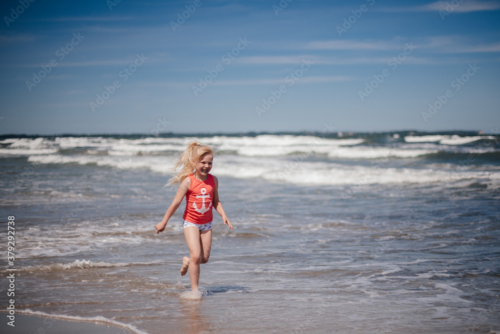 happy child running and jumping in the waves at beach. Reuniting with nature.