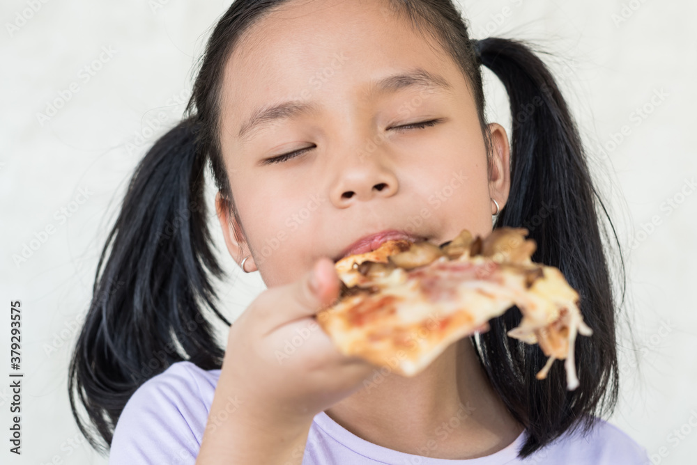 Mmm, so delicious! dark haired little asia girl eats slice of Italian pizza, keeps eyes closed from pleasure, enjoys nice taste, has good appetite, dressed in casual purple shirt, eating concept. Mmm, so delicious! dark haired little asia girl eats slice of Italian pizza, keeps eyes closed from pleasure, enjoys nice taste, has good appetite, dressed in casual purple shirt, eating concept.