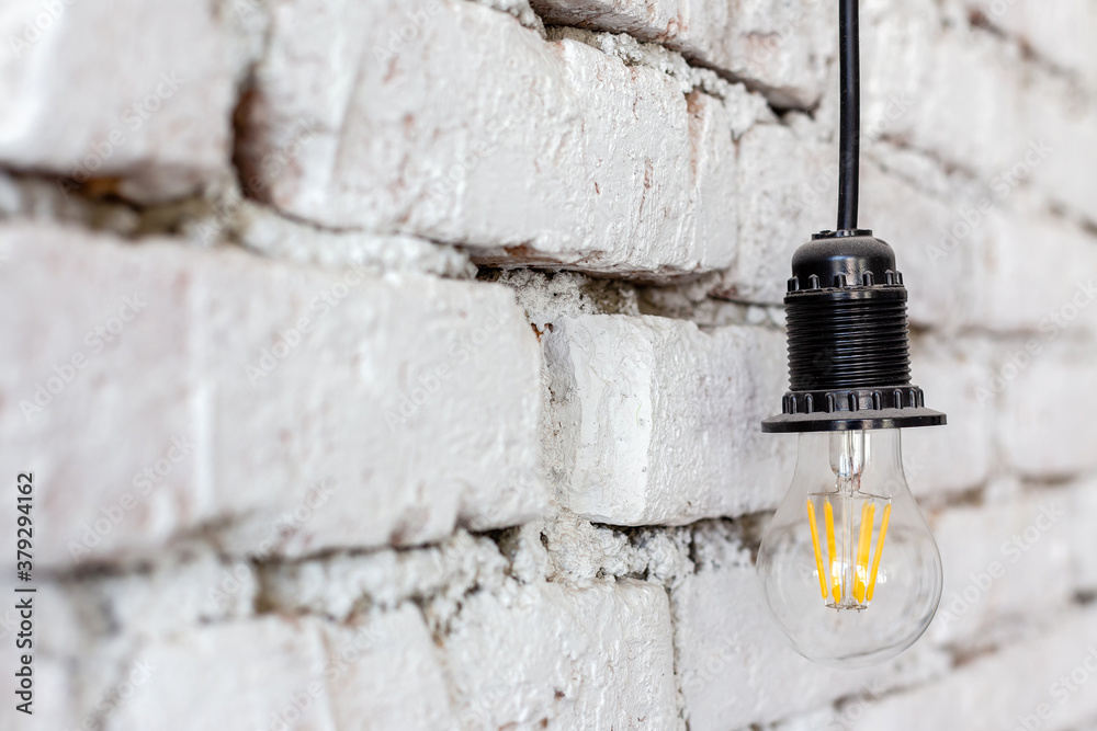 LED lamp hanging on a background of a rough white wall in a luxury design of modern loft hotel room.