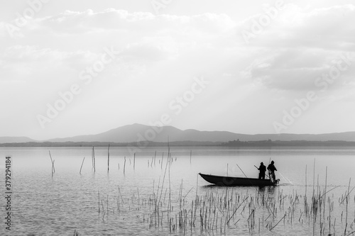 Two men on a little boat fishing in a lake
