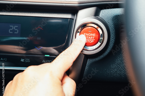 Finger about to touching and press button function start and stop luxury car engine in the automobile on the road trip. Owner and dealership concept