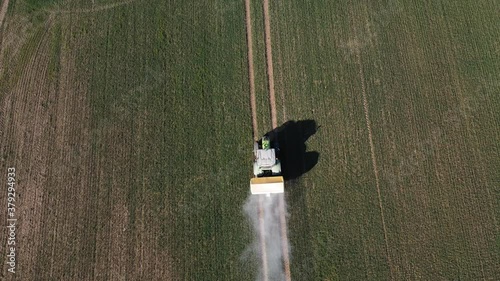 Tractor spreading fertilizers on spring crop field, aerial view

