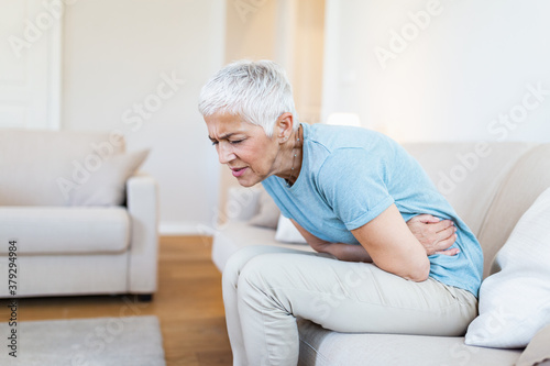 Photo Unhealthy mature woman holding belly, feeling discomfort, health problem concept