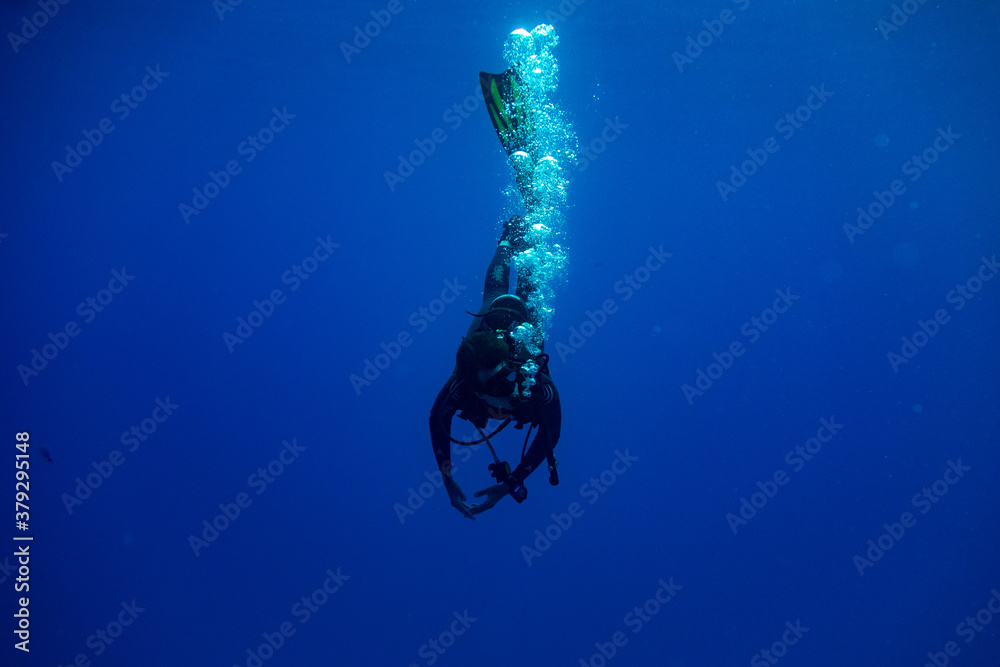 Scuba diver entering water in a vertical position making bubbles Stock