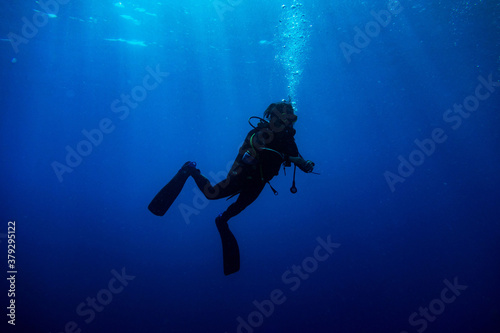 Scuba diver standing in the deep blue with rays of light