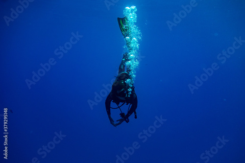 Scuba diver entering water in a vertical position making bubbles photo