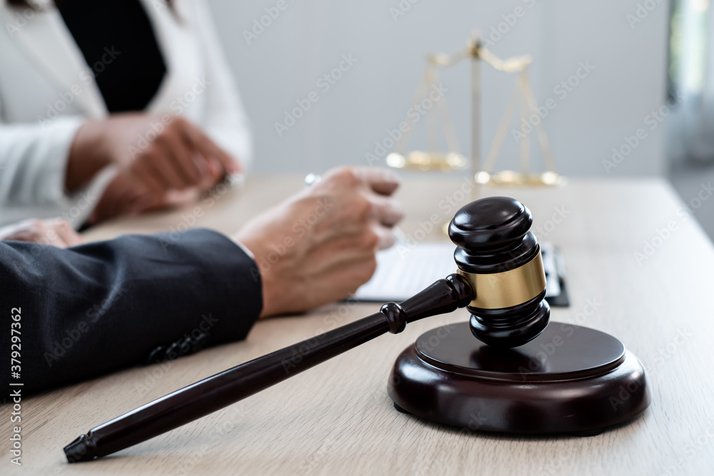 A male lawyer or a judge counseling clients about judicial justice and prosecution with scales, judges gavel, legal documents legal services concept