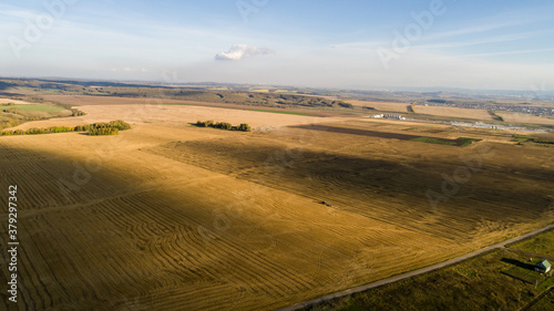 The tractor plows the field for sowing wheat. A beautiful new tractor in the field leaves a strip of beautiful background behind it. Agroindustry. Aerial View work in the field.