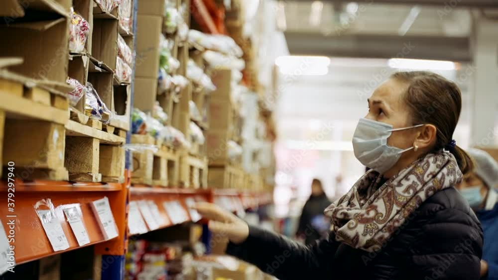 A woman in a black jacket and with a mask on her face buys candy in the store. A woman in a black jacket and with a mask on her face buys candy in the store.