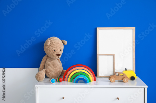 Chest of drawers with toys and blank frames in interior of modern children's room © Pixel-Shot