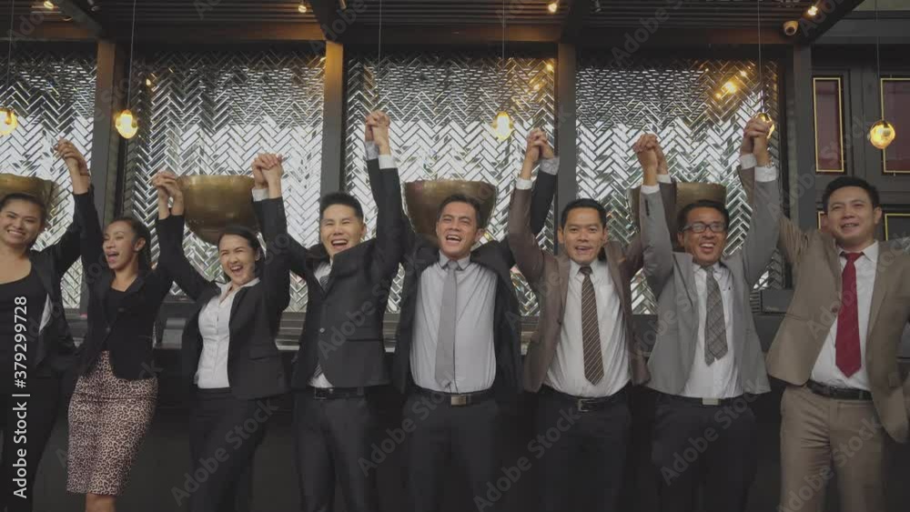 Group of happy Asian business people or employee raising hand up for successful project. company corporate teamwork celebrating together, showing power of unity Group of happy Asian business people or employee raising hand up for successful project. company corporate teamwork celebrating together, showing power of unity