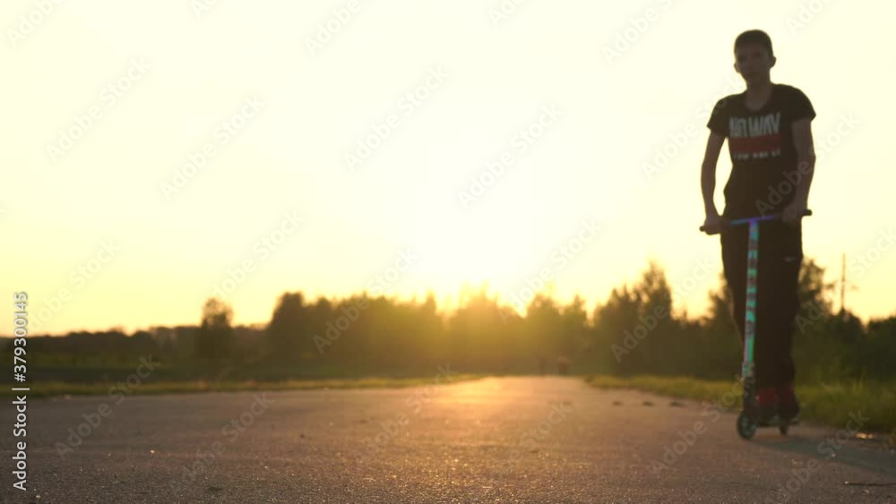 Guy doing tricks on a scooter at sunset
