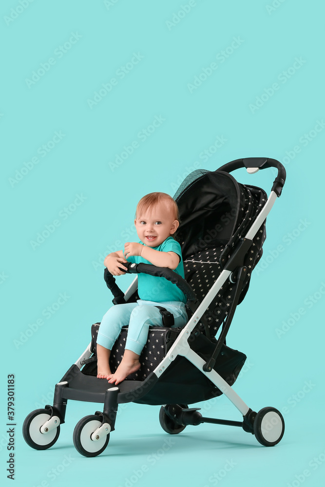 Cute little baby in stroller on color background