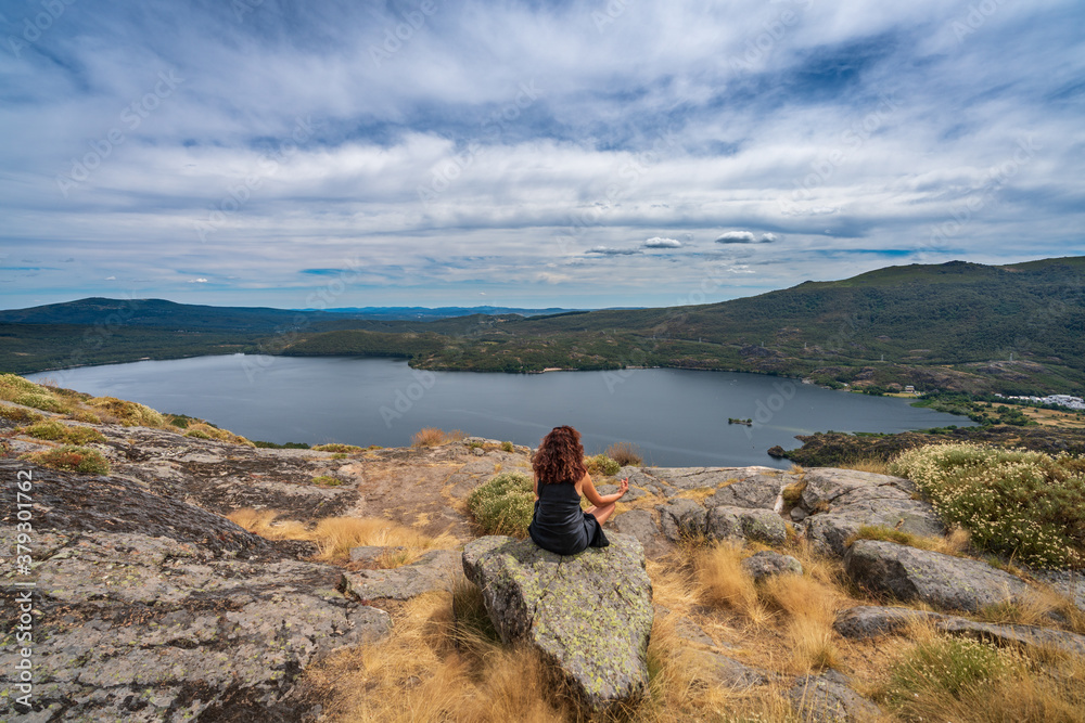 Rear view of unrecognizable woman practising yoga over the lake