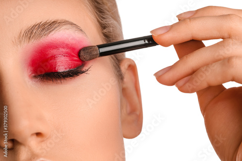 Young woman applying beautiful eyeshadows against white background, closeup