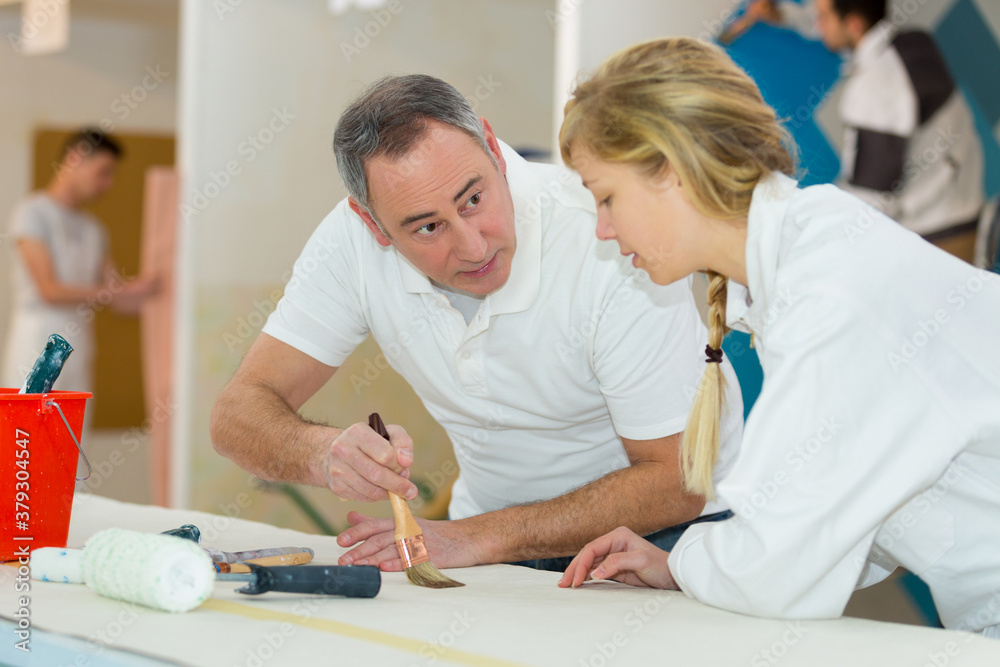 painter teaching paintbrush technique to apprentice