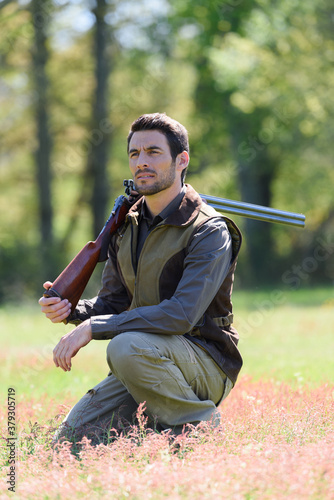 male hunter holding a gun outdoors