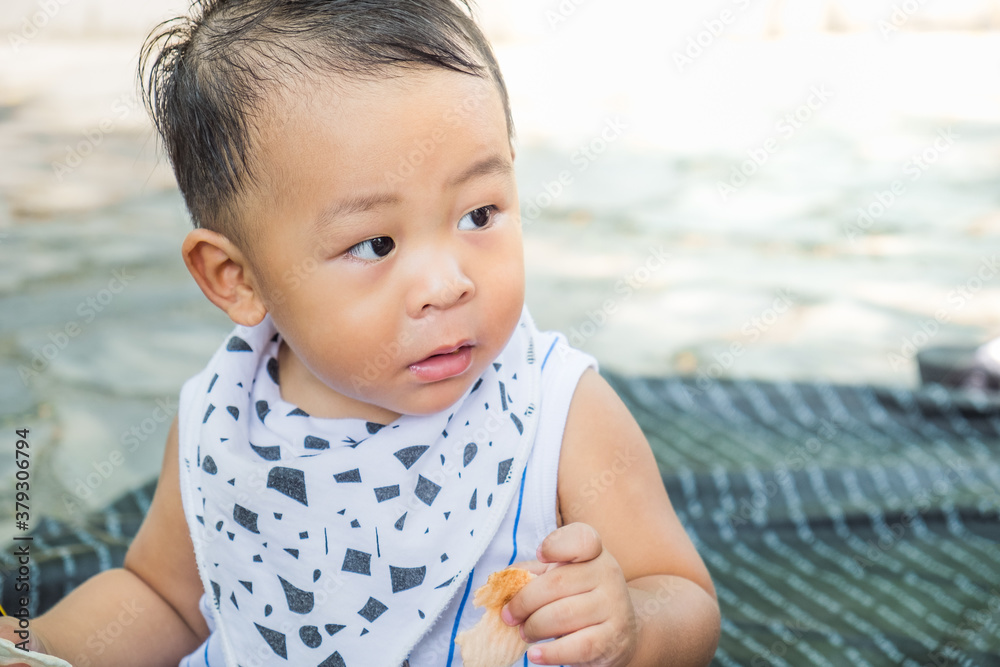 Happy little Asian baby boy eating snack on summer day at the park. Breastfeeding or early childhood development concept Happy little Asian baby boy eating snack on summer day at the park. Breastfeeding or early childhood development concept