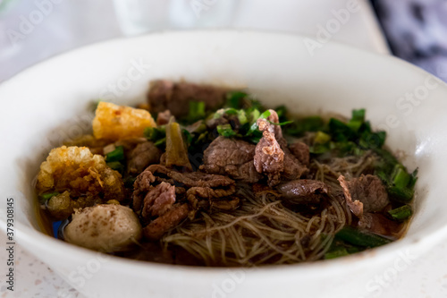 Asian noodles with cooked beef in traditional ceramic bowl. Thai peoples call Boat Noodles.