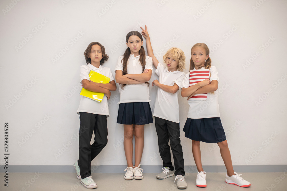Fototapeta premium Schoolchildren standing near the wall and feeling as a team