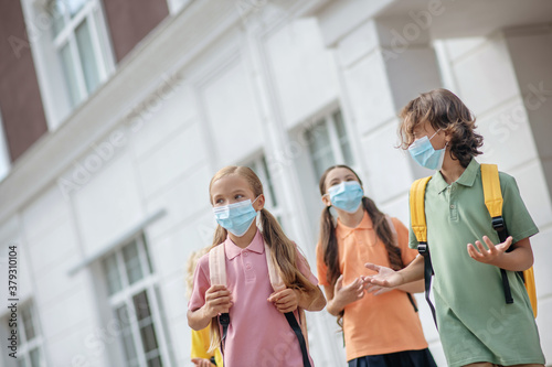 Schoolchildren in protective masks in the school yard after lessons