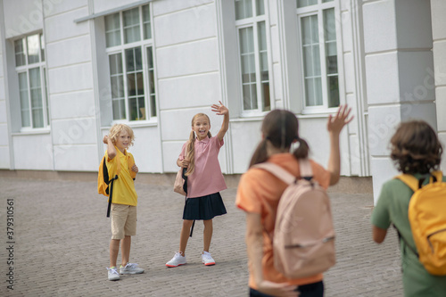 Schoolchildren in the school yard greeting each other keeping distance