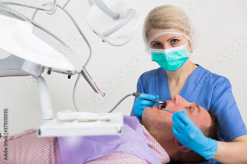 Portrait of female dentist with male patient during dental cure in modern dentistry