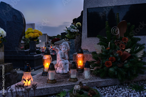 Fotografie rememberance candle lanterns in the cemetery on all saints day with angel statue