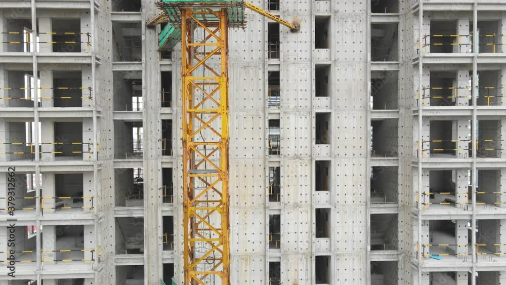 Aerial view drone moving around the building in construction. Real estate development concept crane tower and elevator in the construction site worker working in the window clean lift office apartment Aerial view drone moving around the building in construction. Real estate development concept crane tower and elevator in the construction site worker working in the window clean lift office apartment