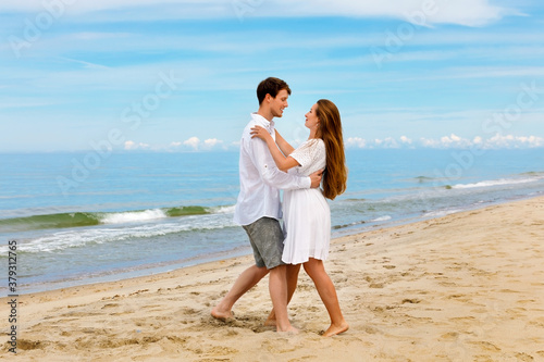 Pleasant couple of young people in love dancing on the sea beach