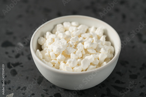 Cottage cheese in white bowl on concrete background
