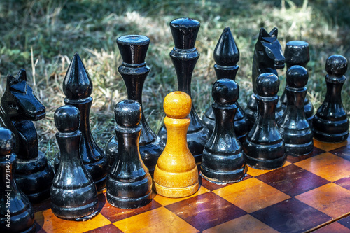 Foto White chess pawn standing with black pieces on the chessboard