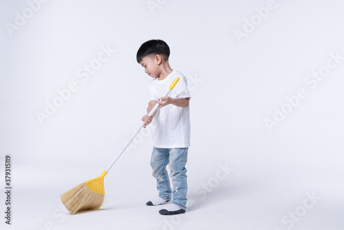 Asian boy doing chore by sweep the house floor with plastic broom