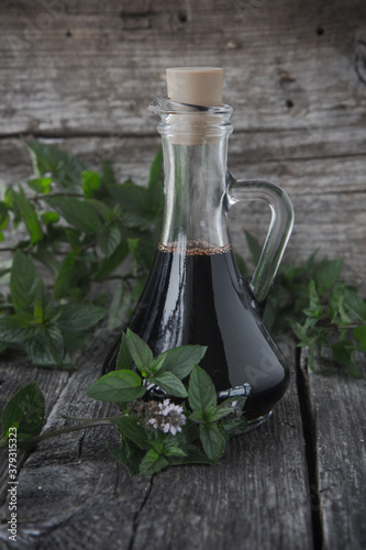 Glass bottle with mint extract and fresh mint flowers.