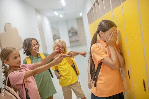 Dark-haired girl closing her face and suffering from bullying
