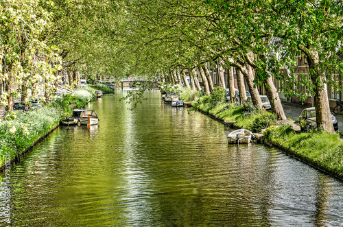 View along the length of Noorder Boerenvaart canal in Enkhuizen, The Netherlands, lined with trees, on a sunny day in springtime photo