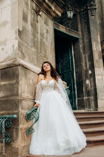 Pretty bride in a vintage dress posing near an old building.