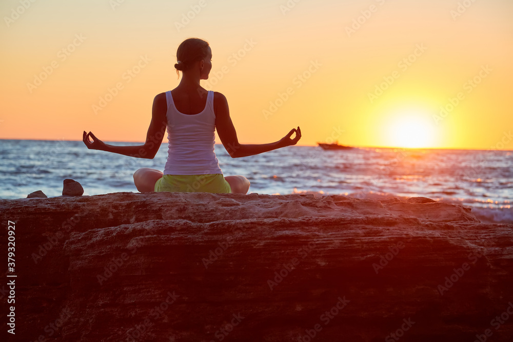 Lady sit in lotus position. Lovely sunset over ocean. Virgin nature landscape. Meditation and yoga concept, copy space