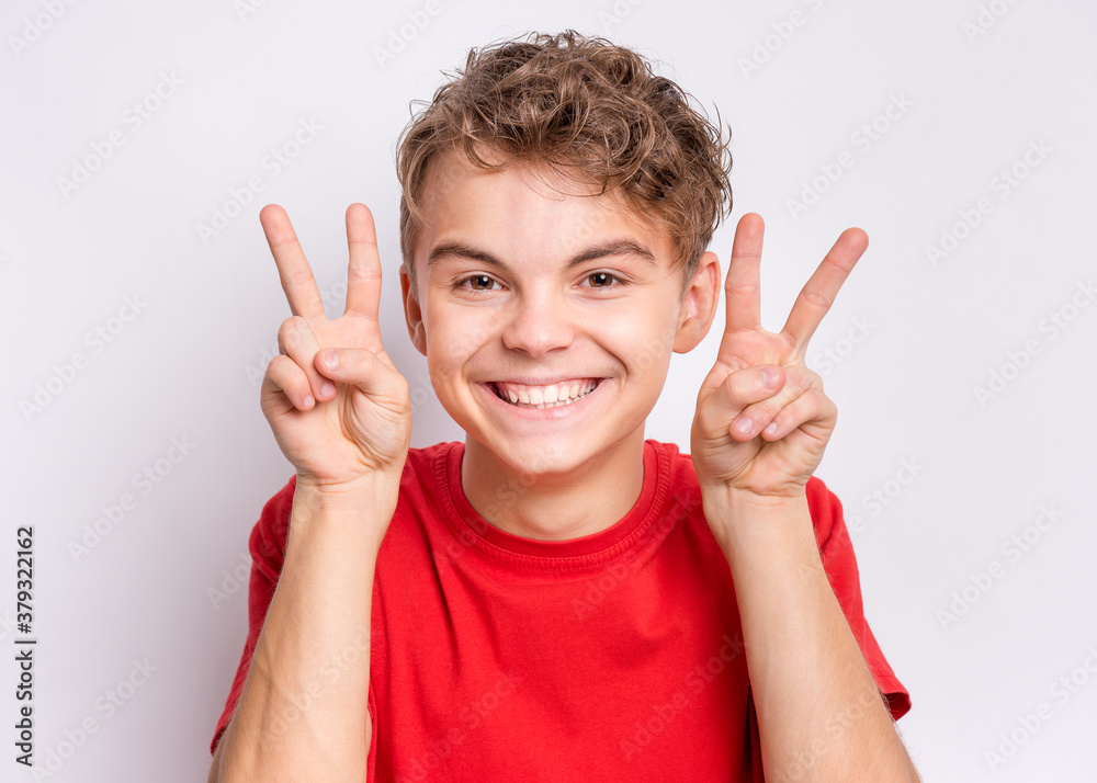 Portrait of teen boy making Victory gesture, on grey background. Handsome caucasian young teenager smiling and showing victory sign. Happy cute child doing victory symbol. Portrait of teen boy making Victory gesture, on grey background. Handsome caucasian young teenager smiling and showing victory sign. Happy cute child doing victory symbol.