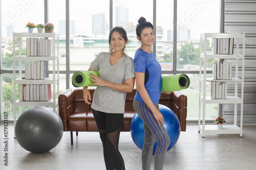 Two middle-aged Asian women are resting and use sweat wipes after exercising at home.