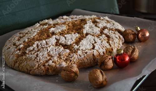 Brot backen mit Nüssen, Nussbrot vor grünem Hintergrund mit Mehl, Christbaumkugeln in rot und weihnachtlichen Farben