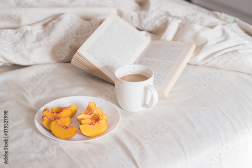 Morning. Cup of coffee  peach and book on the bed  Lifestyle. Mentlhealth. The consept of heathy life.