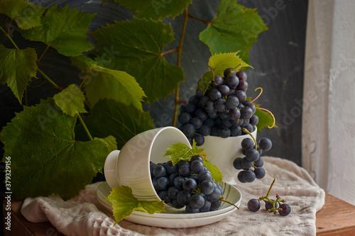 Grapes on a white saucer and a dark background.