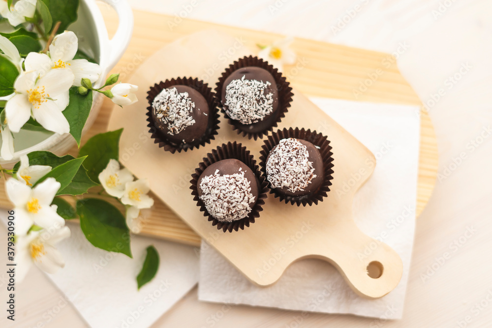 Sweet chocolate balls with coconut lie on a colored white background. In the style of boho and rustic Sweet chocolate balls with coconut lie on a colored white background. In the style of boho and rustic