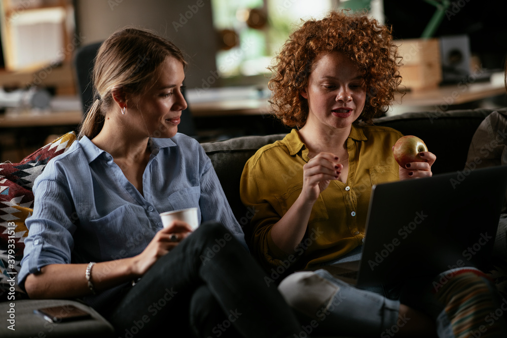 Girlfriends talking and laughing in office. Beautiful women drinking coffee in the office.