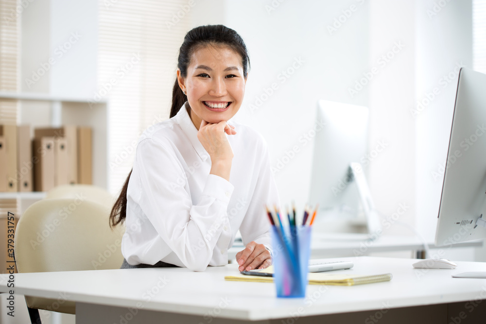 Asian business woman smiling at camera in an office Asian business woman smiling at camera in an office