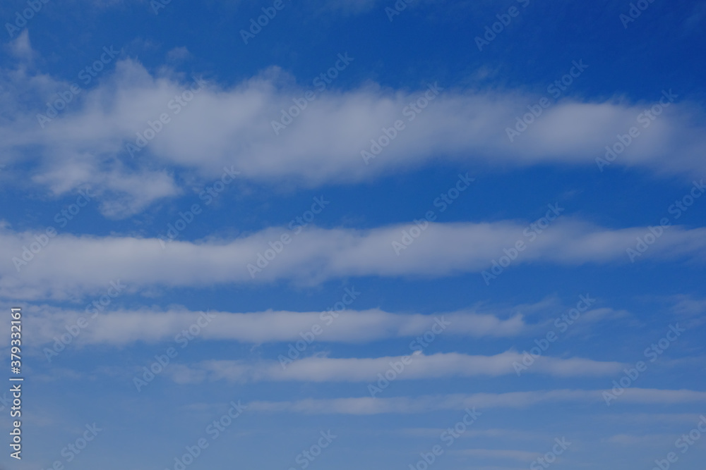 White feather clouds against the blue sky. Striped sky. Background.
